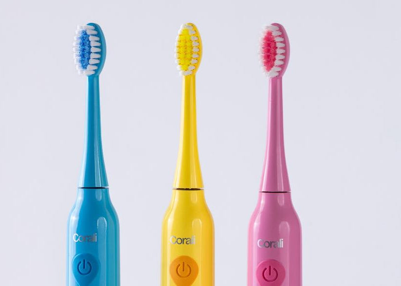 Three colorful children's electric toothbrushes with cartoon designs on a light gray background